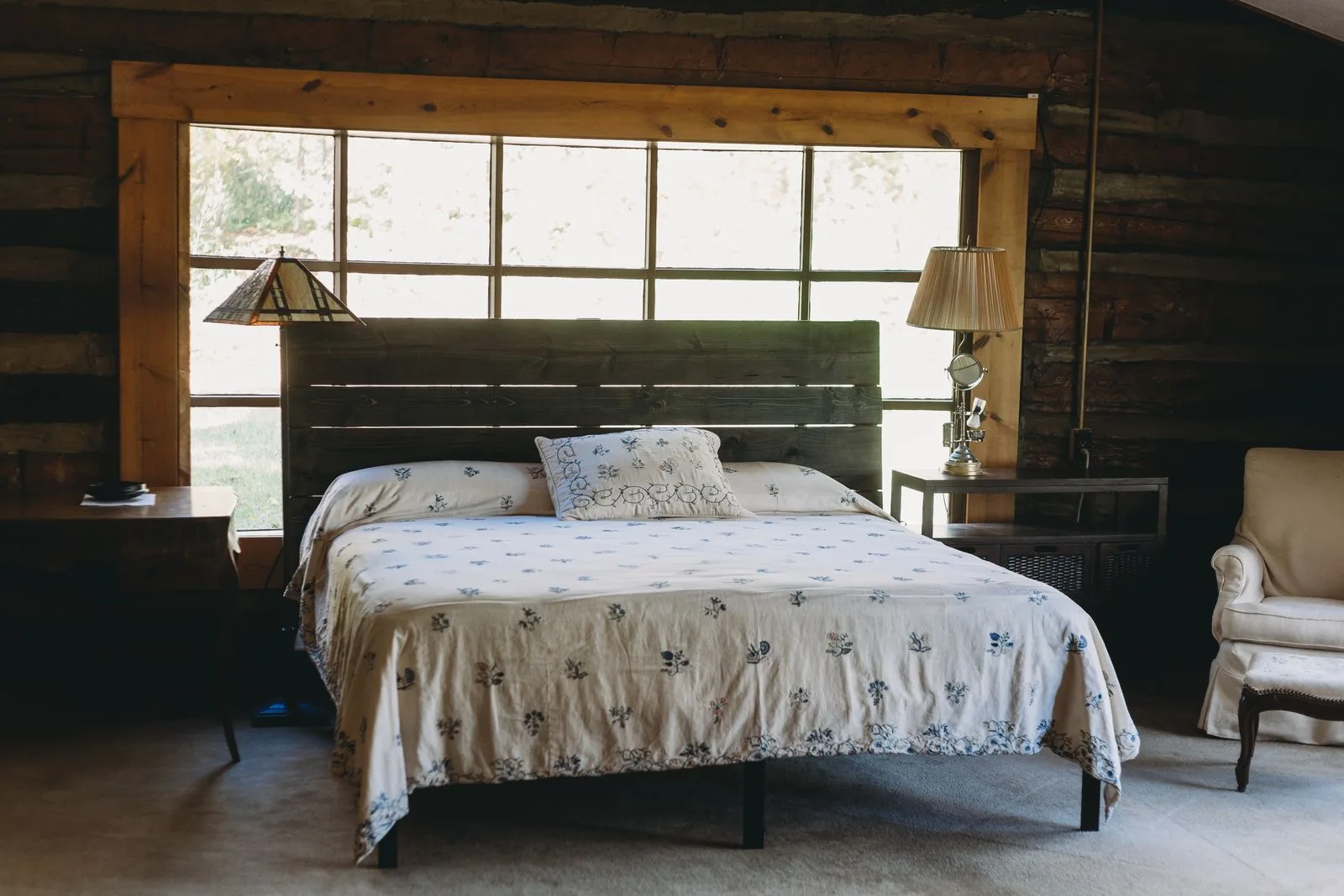 Quarto de referência com madeira, roupa de cama clara e uma janela