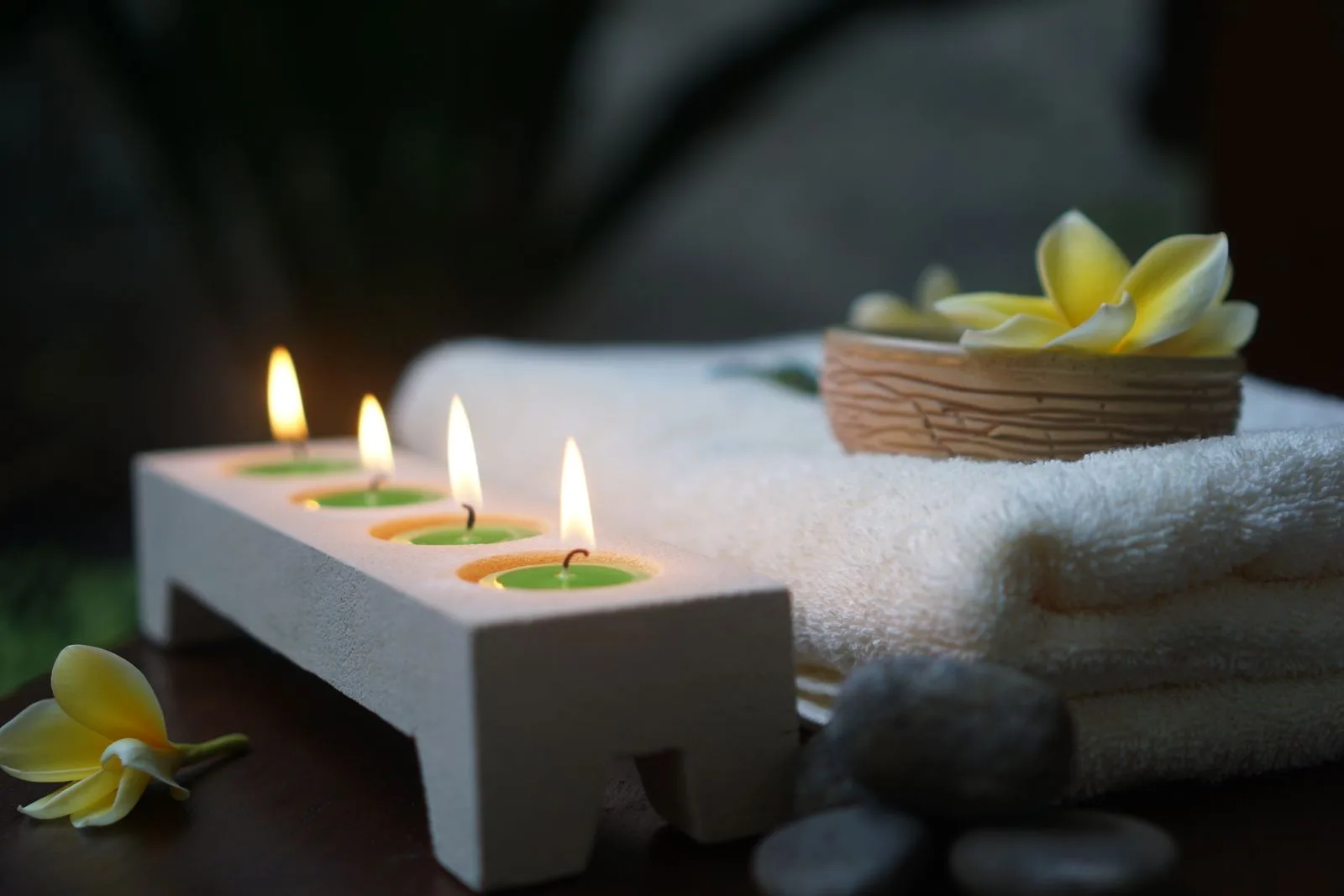 Velas acesas, uma toalha e uma flor num ambiente tranquilo